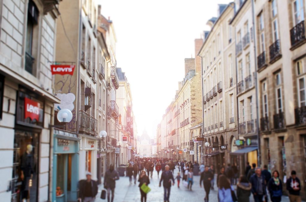 Rue commerçante où l'on voit de nombreux passants et de nombreuses boutiques